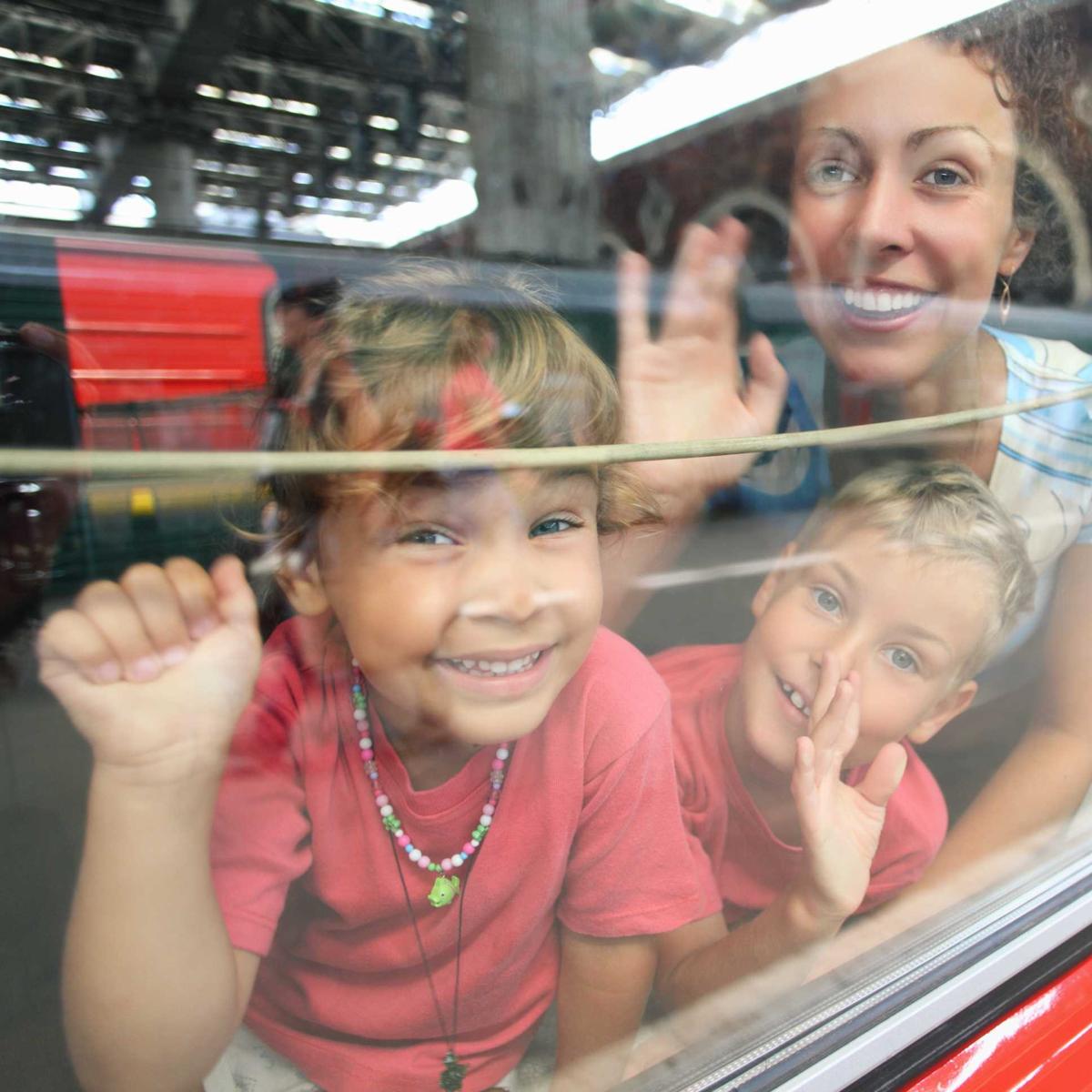eine Familie schaut glücklich auf dem Zugfenster