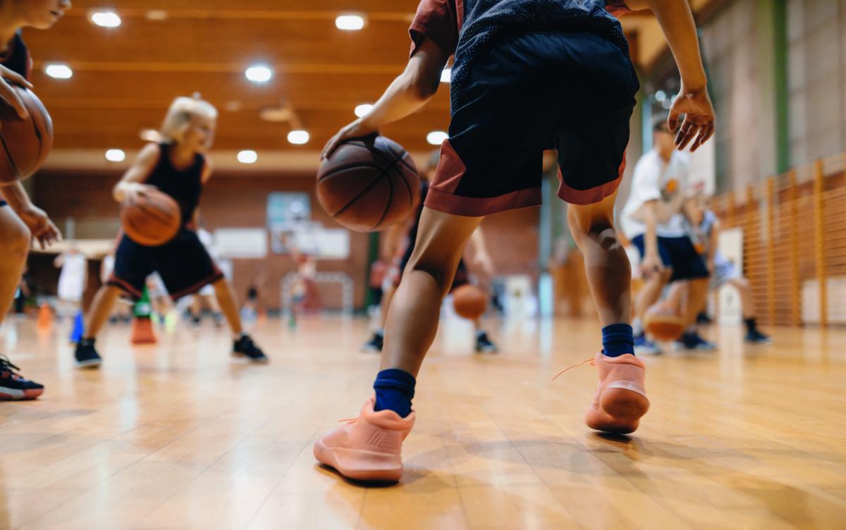 Kinder spielen Basketball in der Turnhalle.