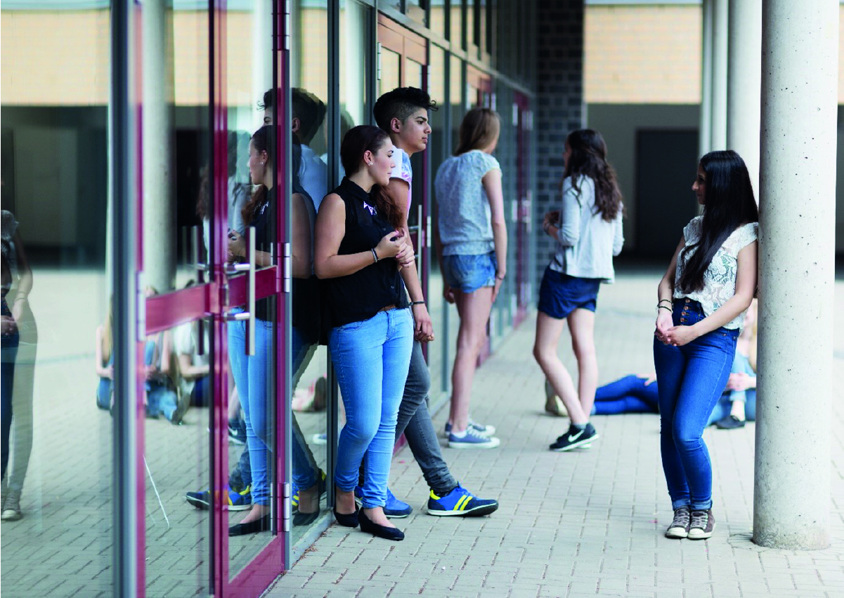 Jugendliche stehen lässig vor dem Schulgebäude