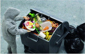 Eine Person wirft Essen in eine Mülltonne.